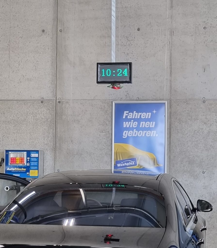 A black car, a poster and a digital clock display